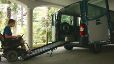 Tekerlekli sandalyedeki adam araç rampası kullanıyor.