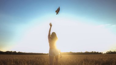 Buğday tarlasında şapkalı bir kız.