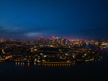 Londra 'nın geceleri göz kamaştırıcı bir manzarası, aydınlatılmış gökdelenler ve Thames nehri, her yerde canlı şehir hayatı var..