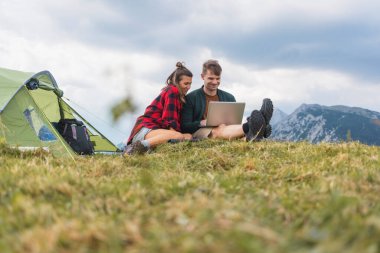 Mutlu kampçı çift rahatlatıcı bir kaçamağın tadını çıkarıyor, doğayla iç içe geçiyor ve bilgisayarla eğleniyor, teknolojiyi ve açık hava macerasını karıştırıyor..