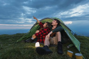 Bir çift çimenli bir tepedeki çadırda oturur, alacakaranlıkta gece gökyüzündeki yıldızları gösterirler. Birlikte neşeli bir anı paylaşıyorlar..