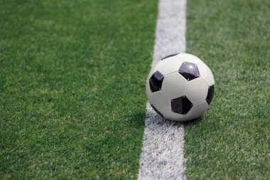 Futbol, antrenmanın başlamasına hazır bir futbol sahasının kenarında duruyor..