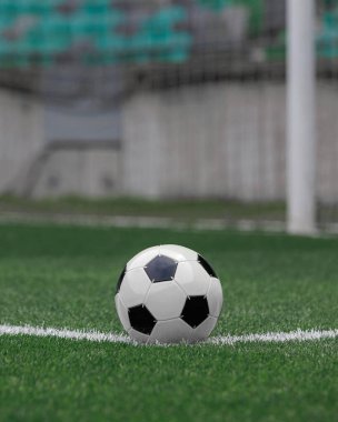 Futbol topu iyi korunan bir çim sahasının köşesinde duruyor, oyun sırasında harekete geçilmesini bekliyor..