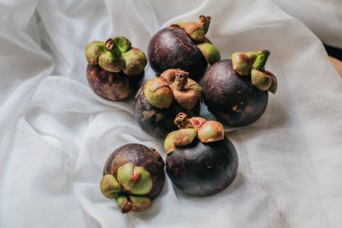 Lezzetli taze mangosteen ve enine kesit bir süpermarkette tropikal meyvelerin kraliçesinin kalın mor derisini ve beyaz etini gösteriyor..