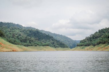 Khun Dan Prakan Chon Dam Nakhon Tayland 'daki güzel göl ve dağ manzarasının panoramik manzarası. Yağmurlu günlerde derin orman gölü kıyıları..