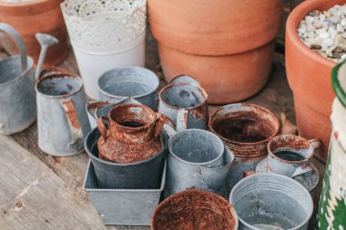 Bahçedeki siyah ahşap bir masa üzerinde evi dekore etmek ya da yeşil terası dekore etmek için eski bir gümüş kap ve kahverengi turuncu kil çömlek..