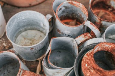 Bahçedeki siyah ahşap bir masa üzerinde evi dekore etmek ya da yeşil terası dekore etmek için eski bir gümüş kap ve kahverengi turuncu kil çömlek..