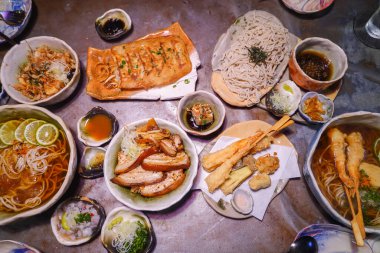 Restorandaki masada lezzetli akşam yemeği çeşitleri Japon yemekleri. Karides tempura, gyoza köftesi, pirinç ve ramen..