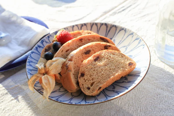 Sabah kahvaltısı için ev yapımı tahıllı ekmek. Güneş ışığı altında lüks beyaz tabakta..