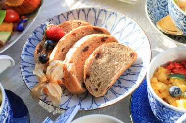 Ev yapımı, keten tohumlu, çilekli ve lüks tabakta yabanmersinli mısır ekmeği. Güneş ışığı altında sağlıklı kahvaltı masası..