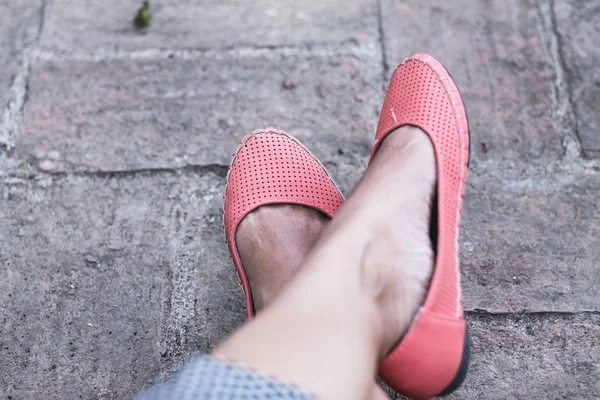 Seyahat ve turizmin covid-19 salgını yüzünden neredeyse durduğunu göstermek için pembe bebek ayakkabısı giyen kadın ayakları.