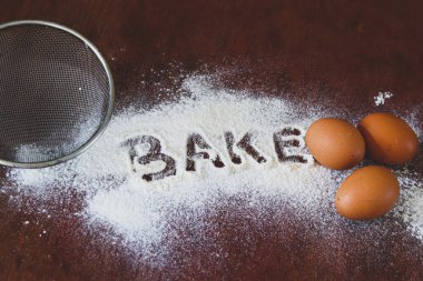 Yumurta ve unun kavramsal natürmort fotoğrafı, covid-19 salgınından dolayı ev karantinası sırasında zihinsel sağlığı desteklemek ve bununla başa çıkmak için bir yol olarak bir masanın üzerine döküldü.