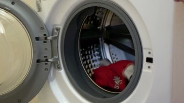 Kadın kirli çamaşırları çamaşır makinesine koyuyor. Kadın çamaşır makinesi kullanıyor..