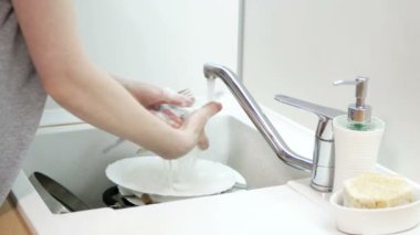 Kadın elleri plastik kaşığı, çatalı ve bıçağı duruluyor. Bulaşık yıkama rutini.