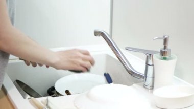 Kadın mutfağa sabun kaşığı ve bıçak uzatıyor. Bulaşık yıkama rutini.