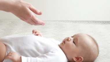 Sevimli bebek annenin parmaklarıyla oynar. Litle bebek annenin eline dokunuyor.