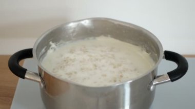 Kişi yulaf lapası tutkal kitle alır. Yulaf ezmesi tavada yulaf lapası pişirir.