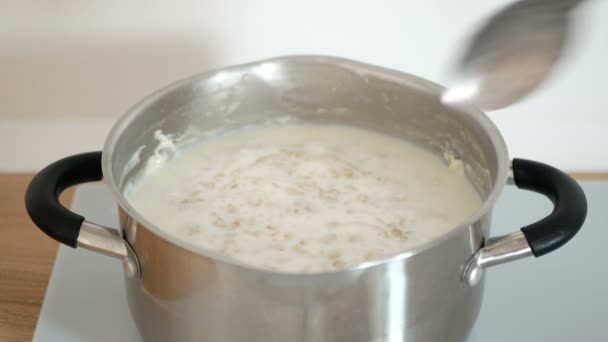 Person mixes oatmeal porridge in pan. Cooking of delicious oat porridge for breakfast. — Stock Footage Person Mixes Oatmeal Porridge Pan Cooking Delicious Oat Porridge Breakfast Royalty Free Stock Footage