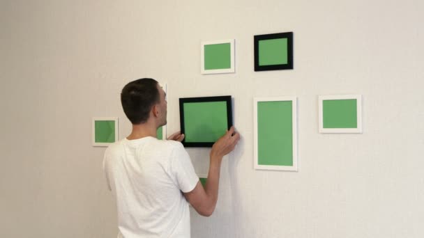 Young Man Hangs Black Photo Frame Wall Man Corrects Photo — Stock Video