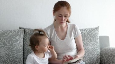 Şirin bir kız ve çekici bir anne fotoğraf izler. Genç anne, kızına fotoğraflarını gösteriyor..