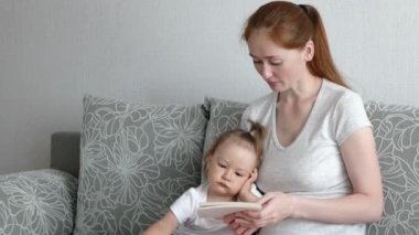 Şirin bir kız ve çekici bir anne fotoğraf izler. Genç anne, kızına fotoğraflarını gösteriyor..