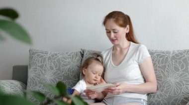 Şirin bir kız ve çekici bir anne fotoğraf izler. Genç anne, kızına fotoğraflarını gösteriyor..