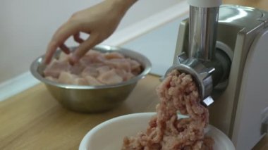 Kıyma öğütülmüş et öğütücüsünden çıkar. İnsan et öğütücüsüne parçalar atar ve elektrikli makineyle doğranmış tavuk hazırlar. Taze doğranmış parçalar kasede. Elektrik kıyma makinesi.