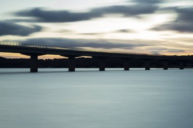 Gece karanlığında, bir göl kapısı viyadük çevrili güneş bulutların üzerinde güzel renklerle