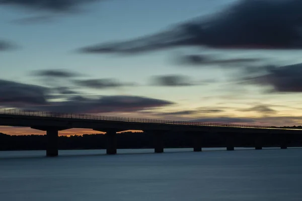 黄昏时 高架桥穿过湖面 周围环绕着云上美丽的阳光颜色 — 图库照片