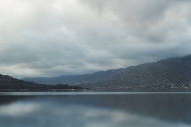Bulutlar tarafından kaplı su yansıtılır Dağları'nın eteklerinde güzel göl