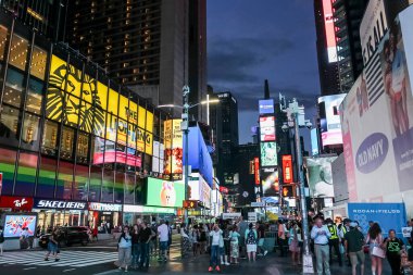 New York, ABD; 19 Haziran 2017: Geceleyin Times Meydanı 'nın tadını çıkaran turistler, yüksek gökdelenleri ve sayısız neon ışıklı billboardlarıyla çevrili