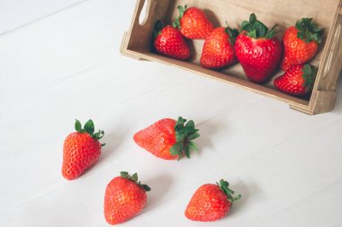 Yatay yakın plan, ahşap bir kutuda taze ve organik çilekler ve beyaz ahşap bir arka plan. Kavramlar, seçici odak, kopyalama alanı