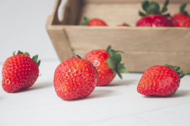 Yatay yakın plan, ahşap bir kutuda taze ve organik çilekler ve beyaz ahşap bir arka plan. Kavramlar, seçici odak, kopyalama alanı