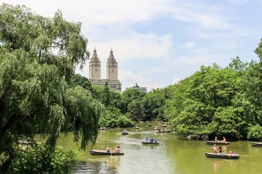 New York, ABD; 22 Haziran 2017; Central Park 'taki sandalların keyfini çıkaran turistler, güneşli bir günde, parkın güzel yeşillikleri ve New York' un yüksek gökdelenleri ile çevrili.