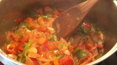 Yakın çekim, kırmızı ve yeşil biber, soğan ve havuç bir tencerede kaynatılmış, sağlıklı yemek için hazır, 4k