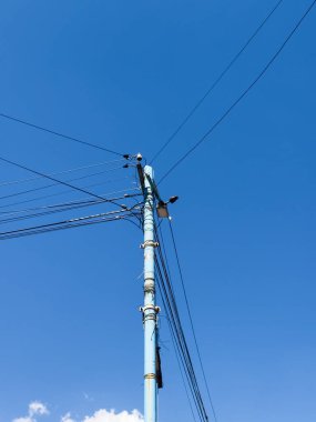 Üzerinde kablolar olan mavi bir direk. Direk gökyüzünde.