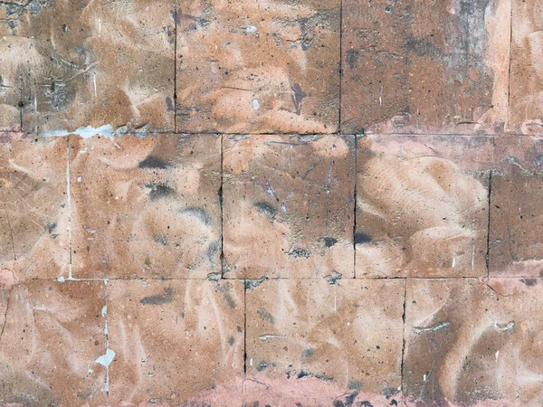 Kahverengi renkli tuğlalardan yapılmış bir duvar. Duvarın kaba bir dokusu var. Tuğlalar mükemmel hizalanmamış.