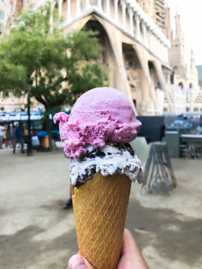 Elinde pembe ve beyaz kıvrımlı dondurma külahı tutan biri. yüksek kalite