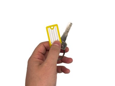 Anahtarlar, kapı anahtarları, ev anahtarları, ofis anahtarları. Yeni bir dairenin anahtarları, ipotek, kira, konut, ev satın alma, ipotek, ev kirası. Sarı anahtarlıklı anahtarı tutan bir el.