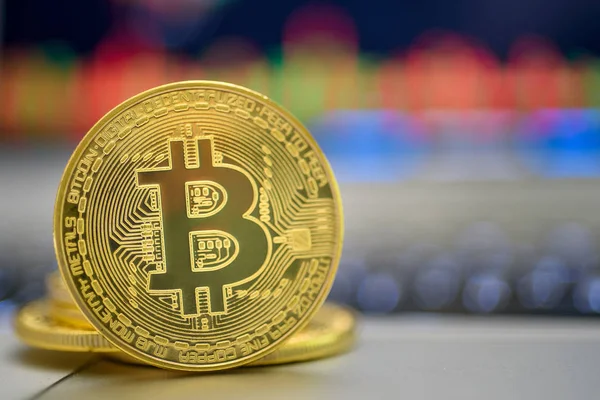 Ticaret grafikler ile laptop yakınındaki bir kaburga üzerinde altın parlak bitcoin duran