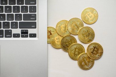 Gümüş bir dizüstü bilgisayar tarafında yukarıdan görünen altın bitcoins