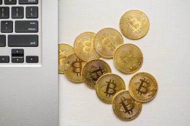 Gümüş bir dizüstü bilgisayar tarafında yukarıdan görünen altın bitcoins