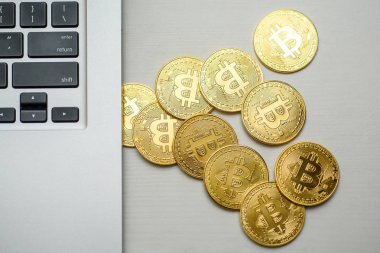 Gümüş bir dizüstü bilgisayar tarafında yukarıdan görünen altın bitcoins