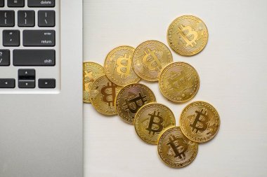 Gümüş bir dizüstü bilgisayar tarafında yukarıdan görünen altın bitcoins