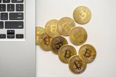 Gümüş bir dizüstü bilgisayar tarafında yukarıdan görünen altın bitcoins