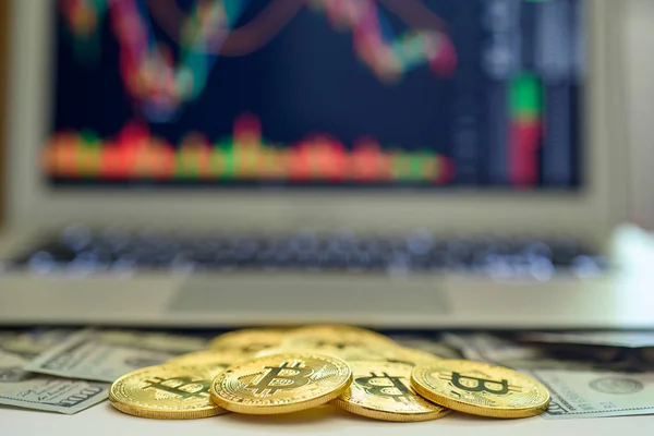 Menkul Kıymetler Borsası grafikler üstünde belgili tanımlık perde ile bir dizüstü bilgisayar yukarıda görünen altın bitcoins ve dolar faturaları