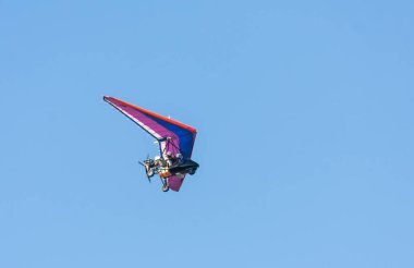 Mavi gökyüzünde uçan iki pilot ile renkli planör