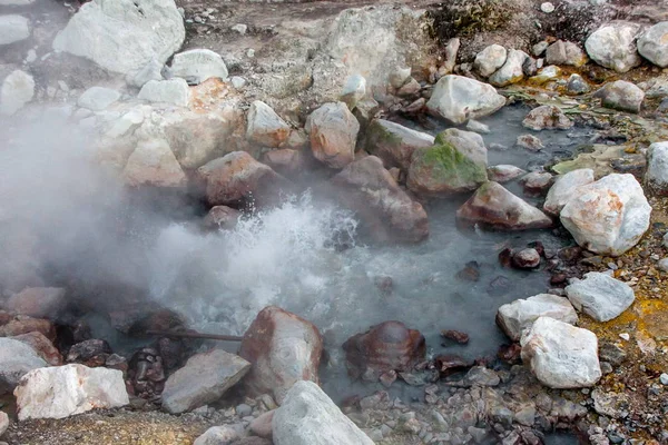 Gischt aus einer heißen Schwefelquelle, die mit großen Felsbrocken übersät ist — Stockfoto