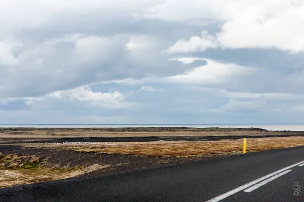 Paisaje con carretera, horizonte, agua y nubes altas - Islandia — Foto de Stock