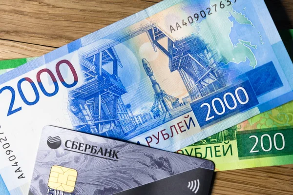 Dinero y tarjeta de crédito Sberbank sobre un fondo leñoso — Foto de Stock